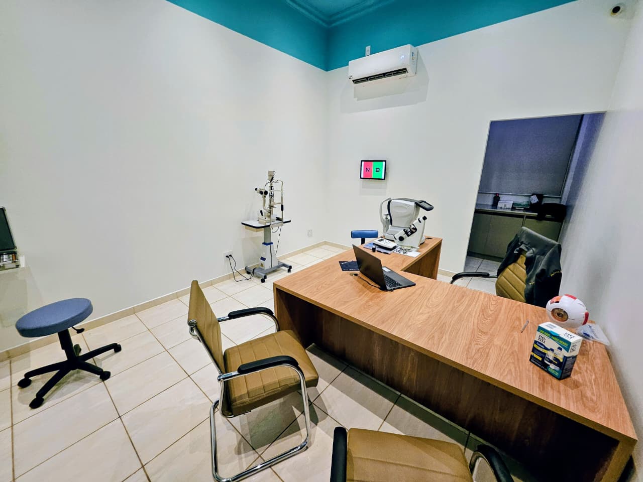Consultório da Clínica Alta Visão com foróptero, lâmpada de fenda e painel de acuidade visual